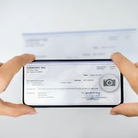 Hands holding phone taking a picture of a check.