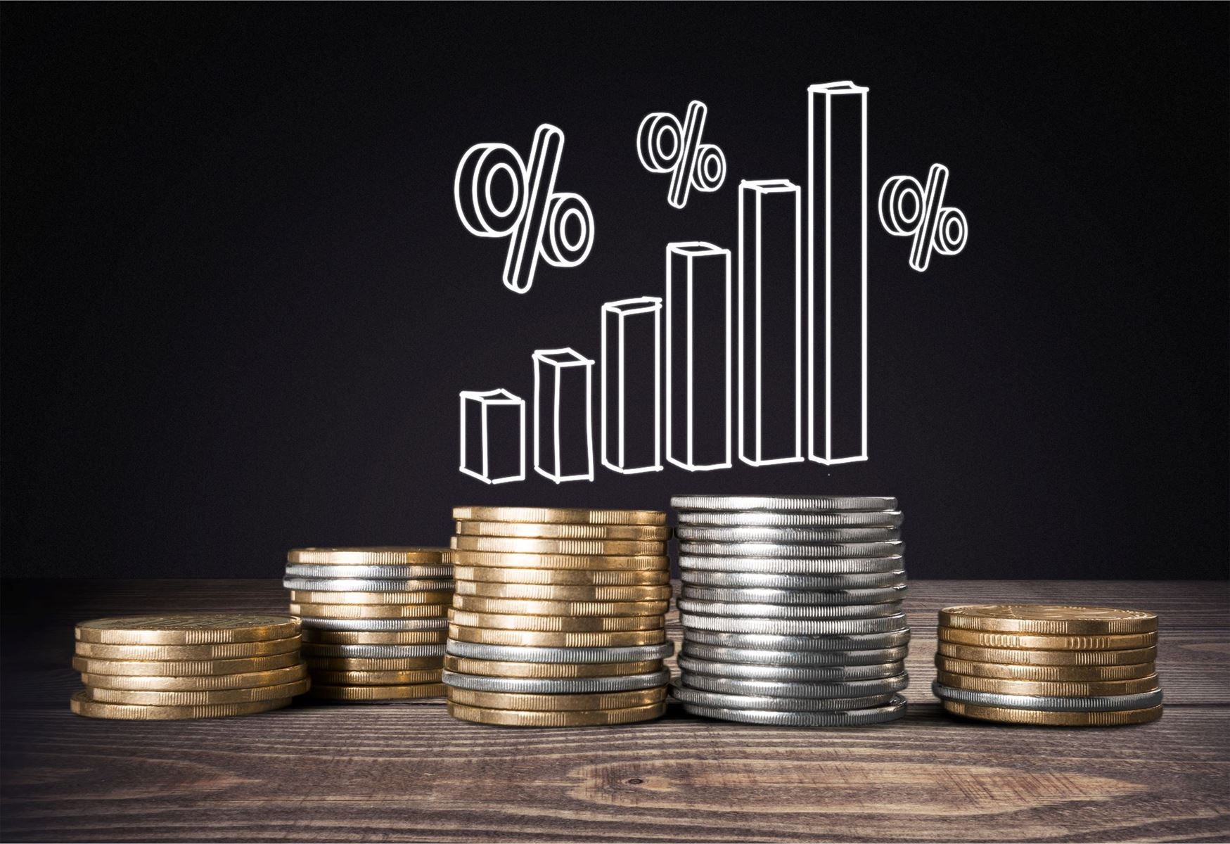 Coins stacked on a table with a drawing of a bar graph and percent signs about the coins