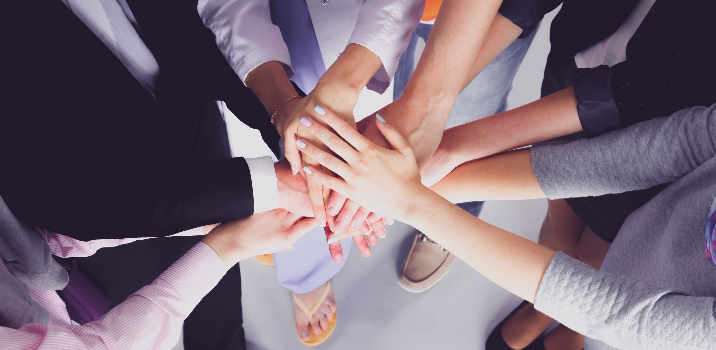 multiple people stacking their hands on top of each other, all hands in